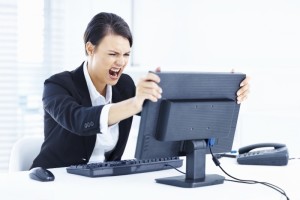 Portrait of a young business woman holding computer monitor in anger